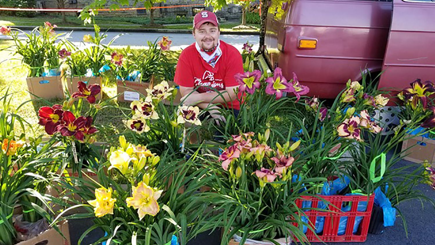 Man sitting among pots of colorful flowers