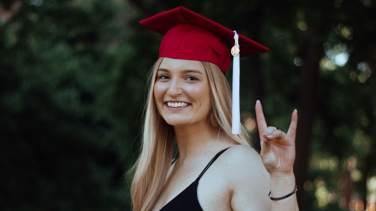 Alex Blanchard wearing her red graduation cap and holding up wolf ears.