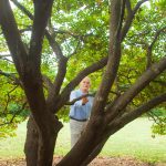Man stands underneath a redbud tree