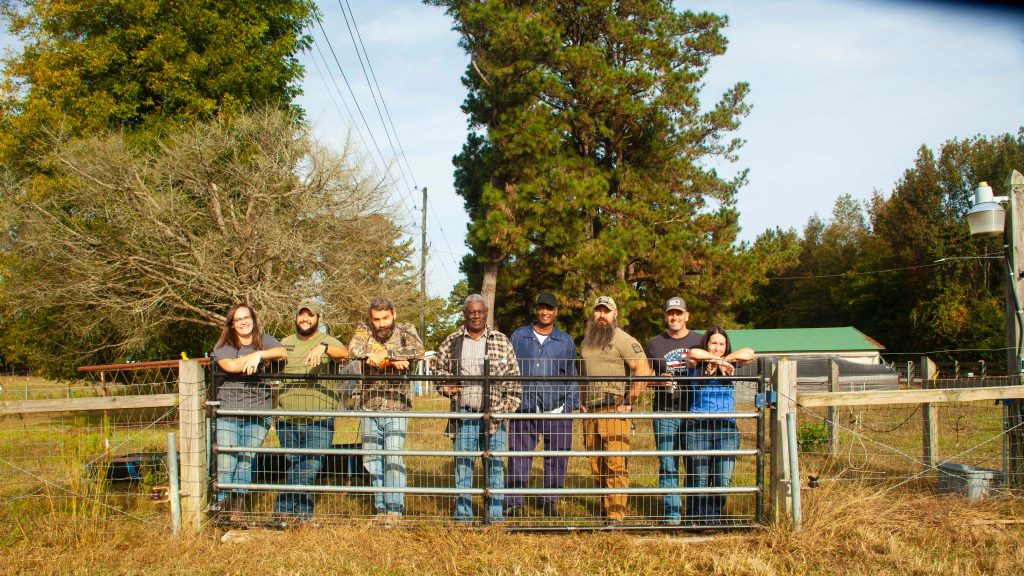 A group of veterans stand by a fence at Sara Kidd's farm.