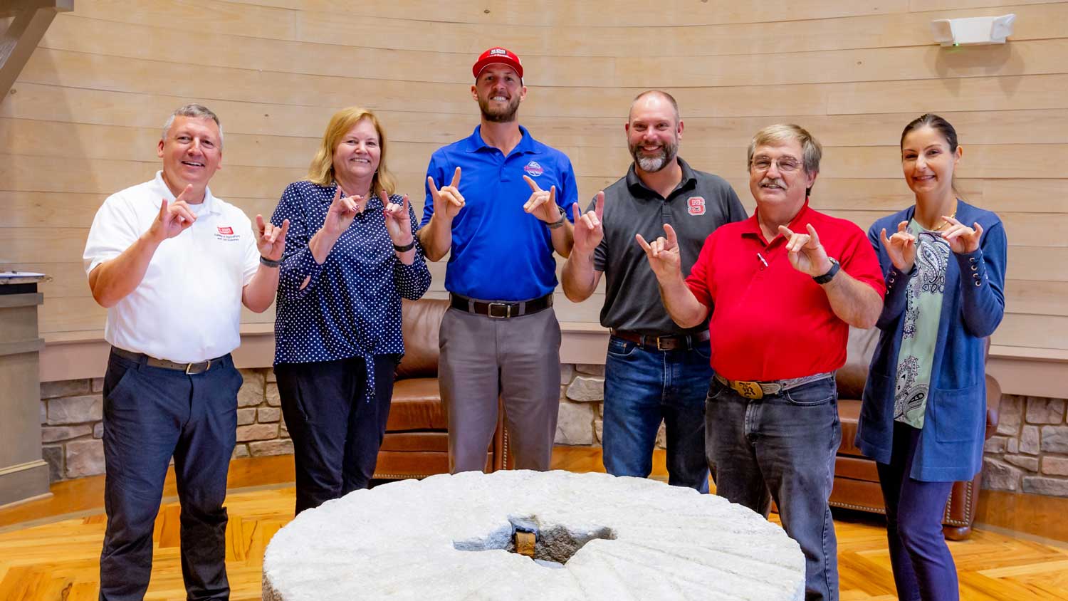 A group of people holding up NC State Wolfears