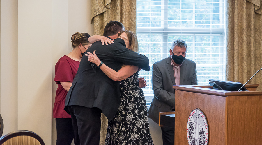 A surprised Janis McFarland hugs Vern Hawkins after learning the internship endowment was announced in her name.