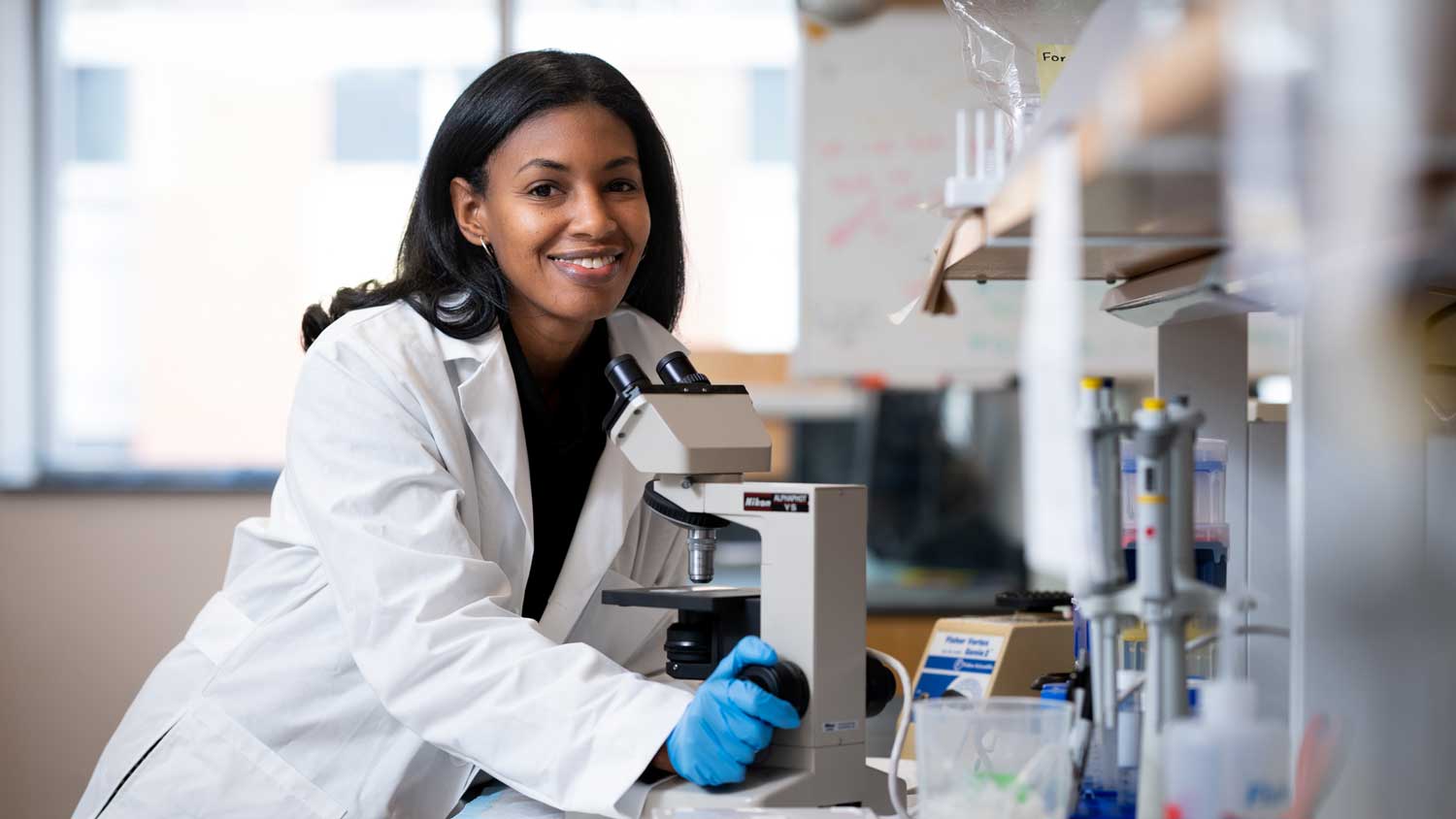 A black female researcher using a microscope in a lab