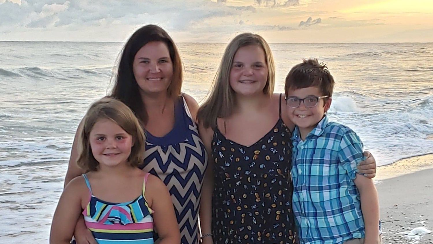 This is a photo of online graduate Rhonda Peters and her three children at the beach.