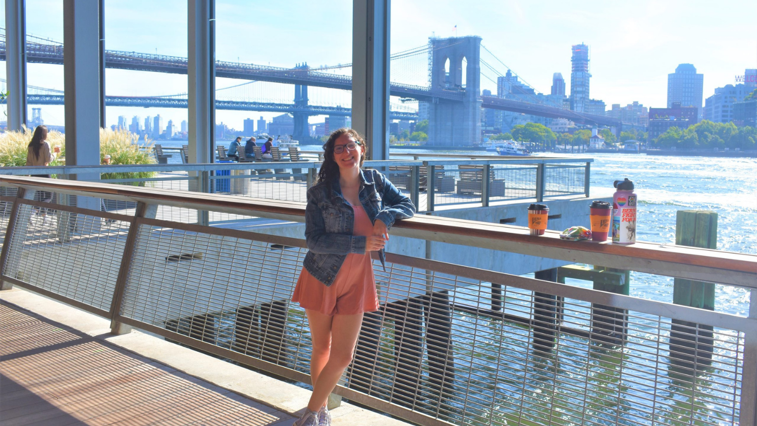 a woman standing with a bridge in the background smiling