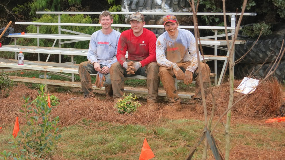 three men that are muddy on bench