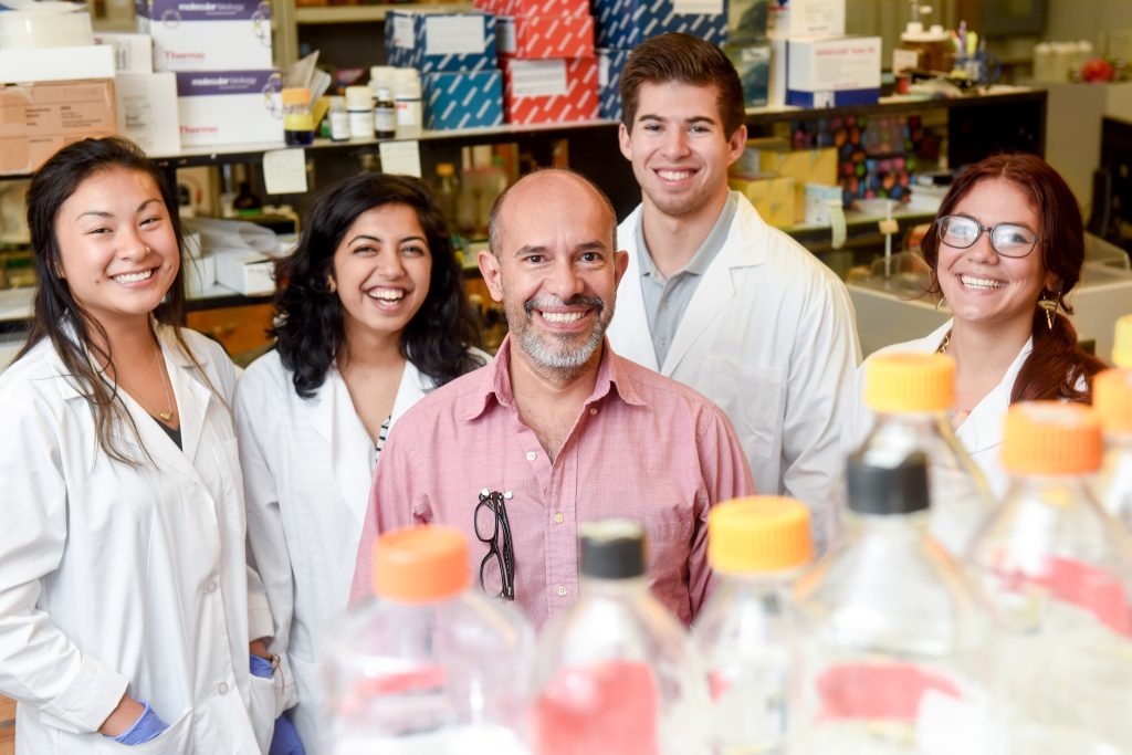 Dr. Trino and students smile in the lab.