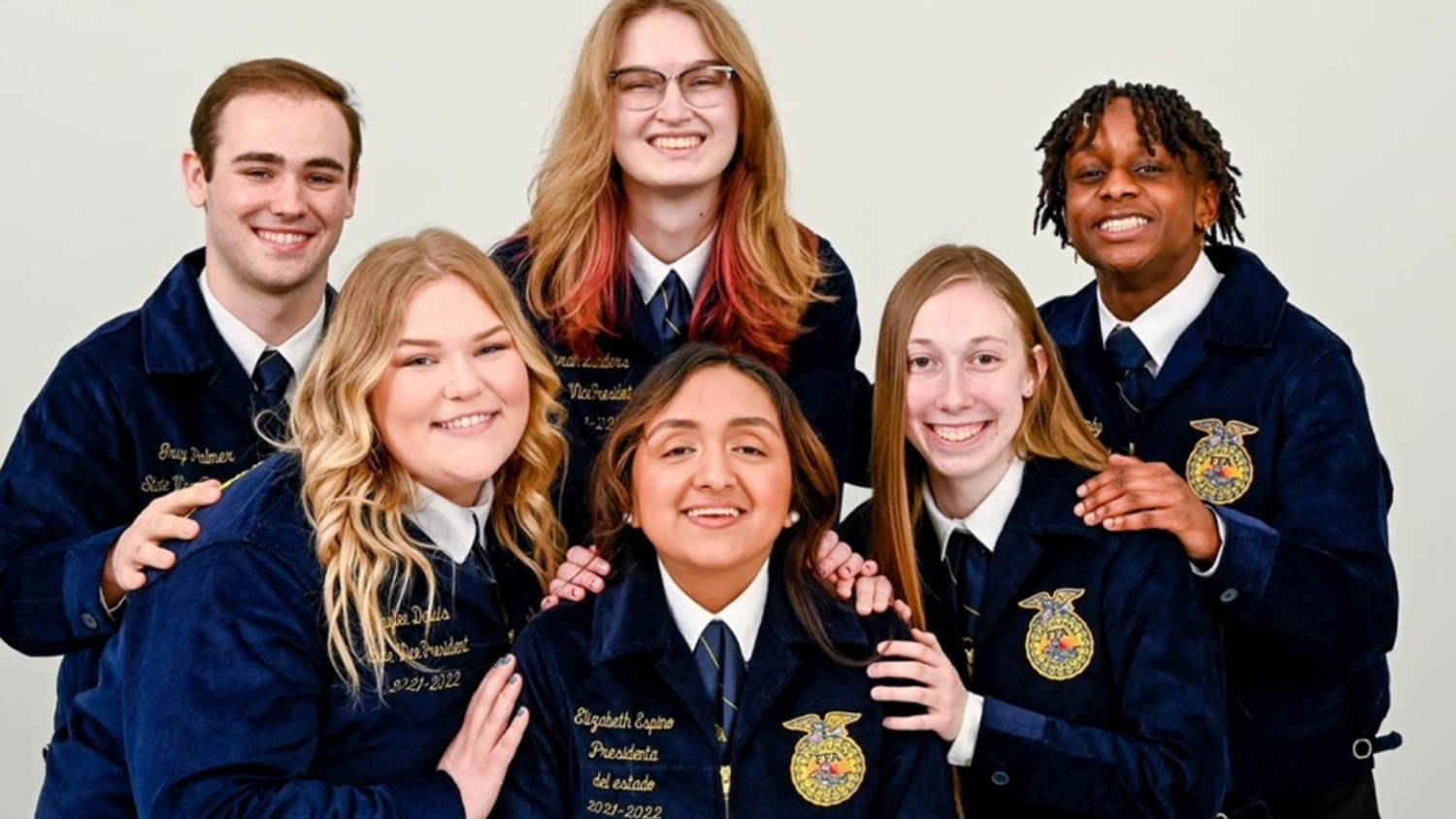The 2021 NC FFA state officers smiling and wearing blue corduroy jackets.