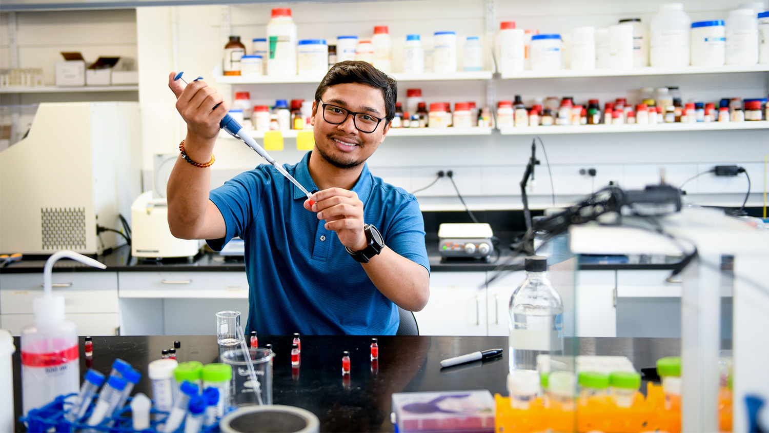 Suman Das posing with a volumetric pipette.