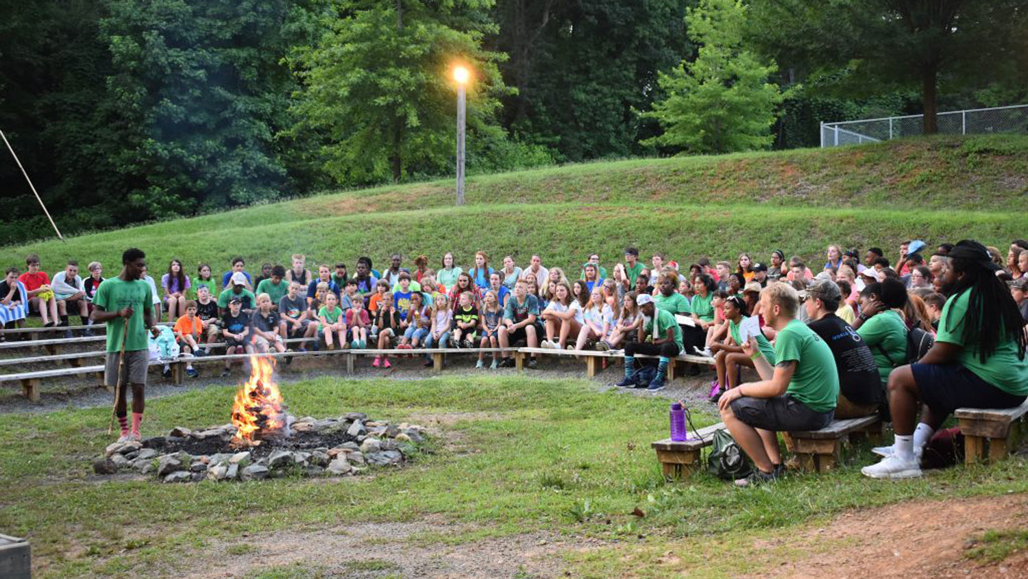 a large group of campers sitting around a campfire