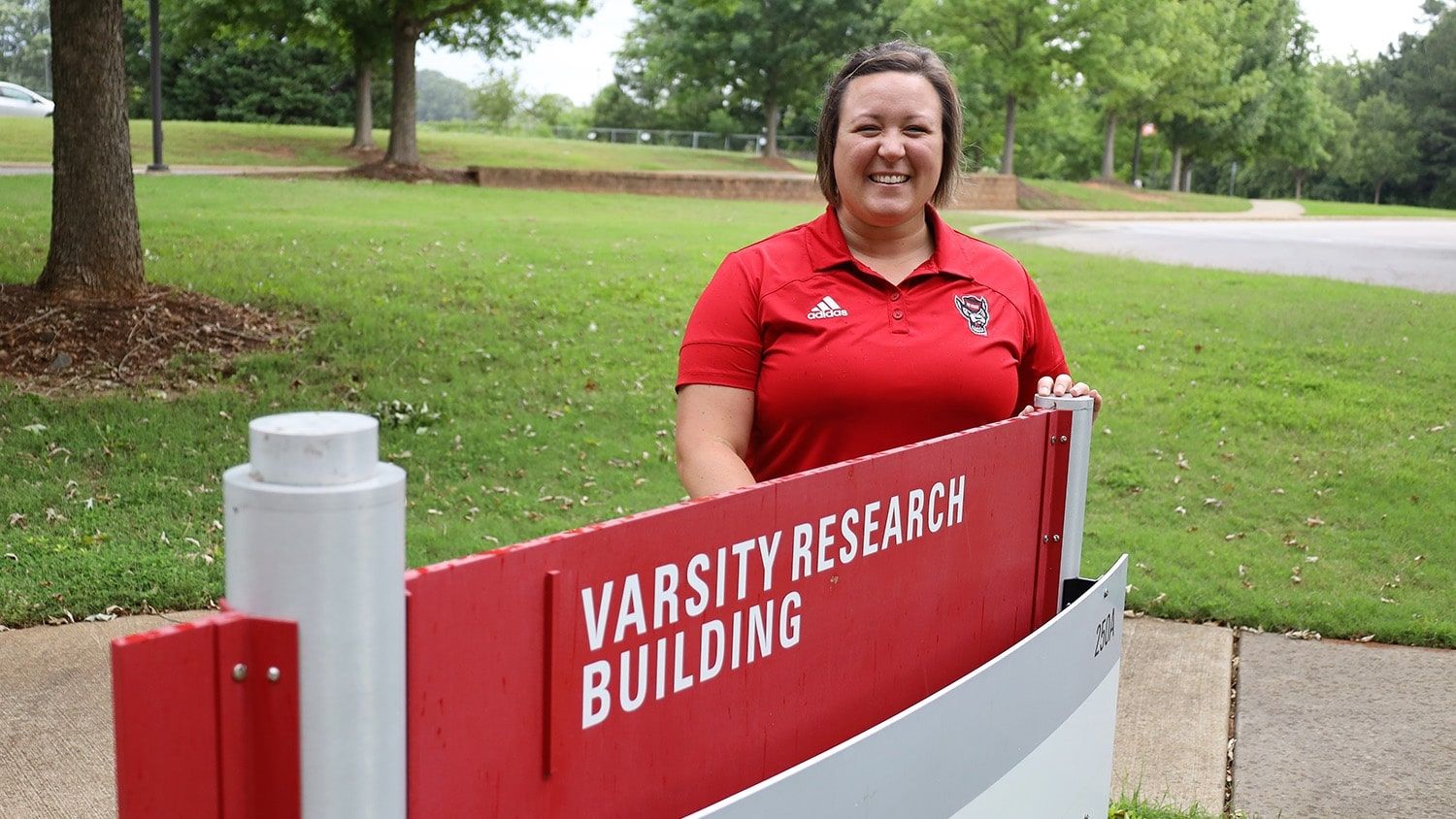 Brandi Merrick in front of a sign for the Varsity Research Building at NC State.