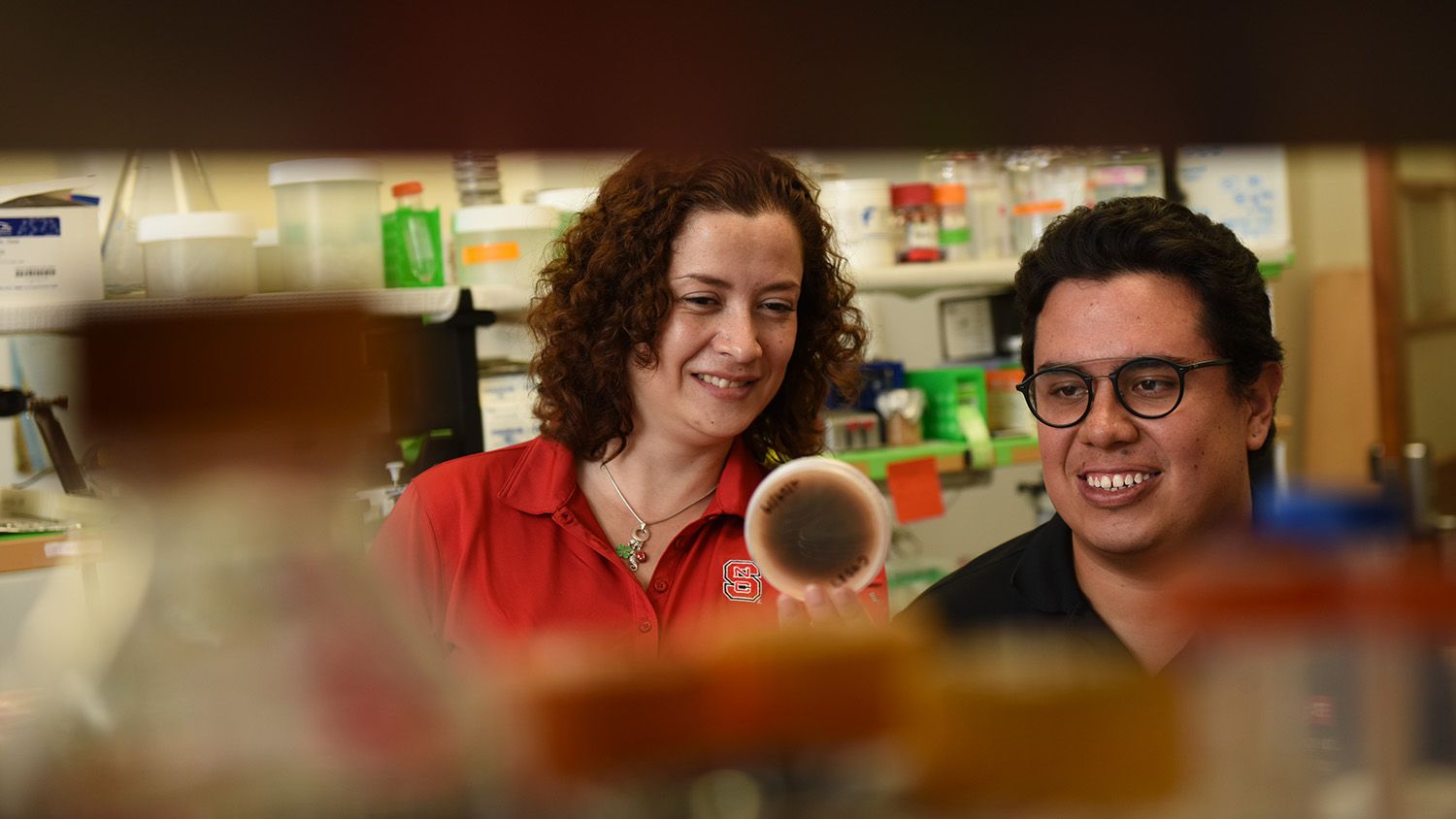 Two researchers holding up a petri dish.
