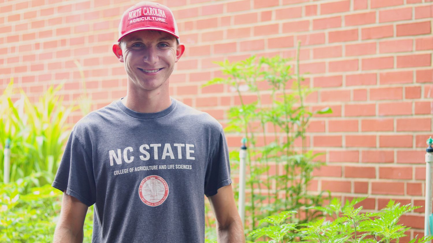 an young male NC state student wearing an NC State hat and shirt