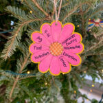 A flower ornament on Christmas. tree with writing.