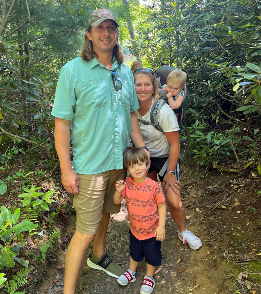 The Moore family standing in woods together