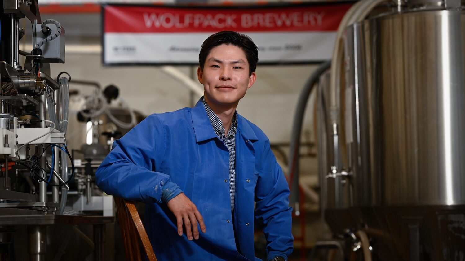 a male undergraduate student sitting in the WolfPack Brewing Lab.