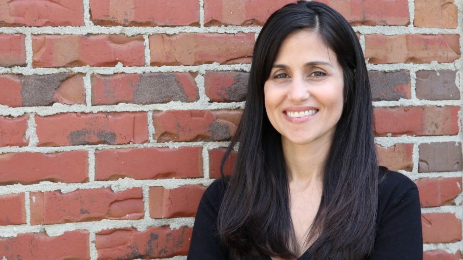 Maru Gonzalez taking a picture in front a brick wall