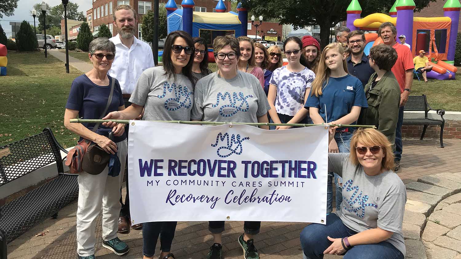 Group holding a "We Recover Together" banner