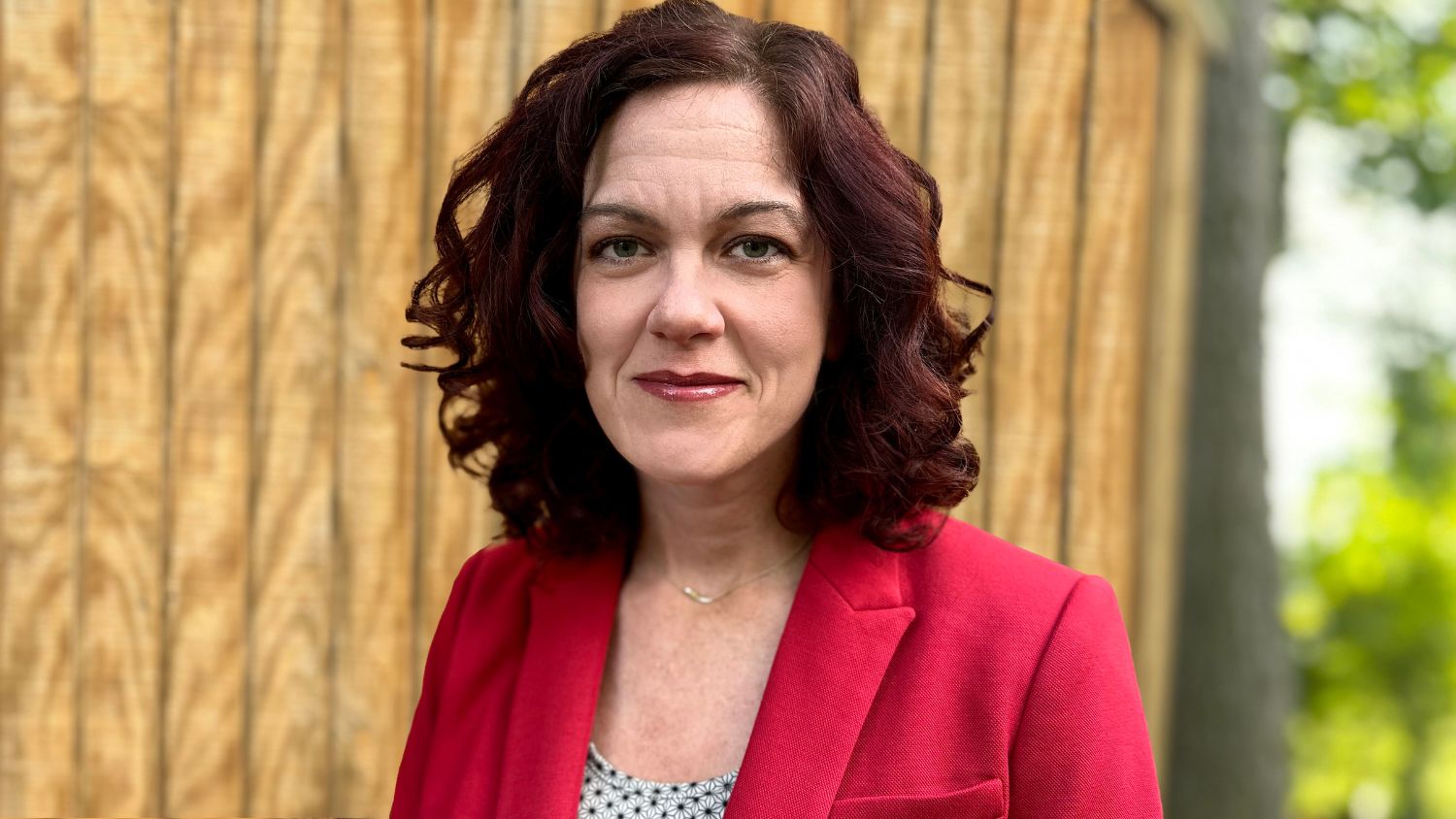 Megan Lybrand wearing a red blazer in a headshot