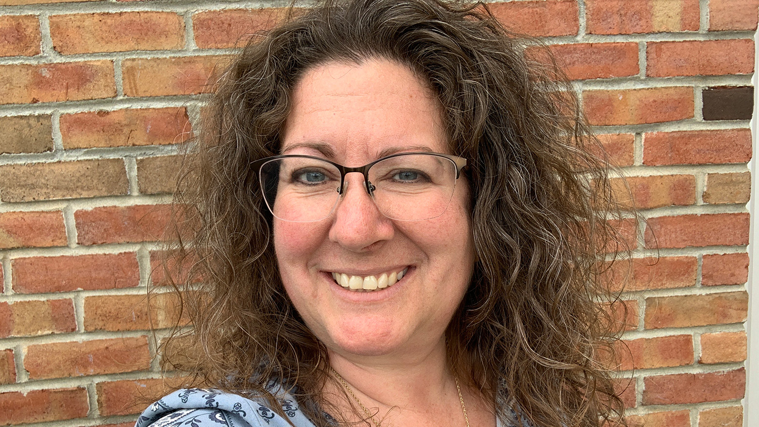 Woman smiling in front of a brick wall