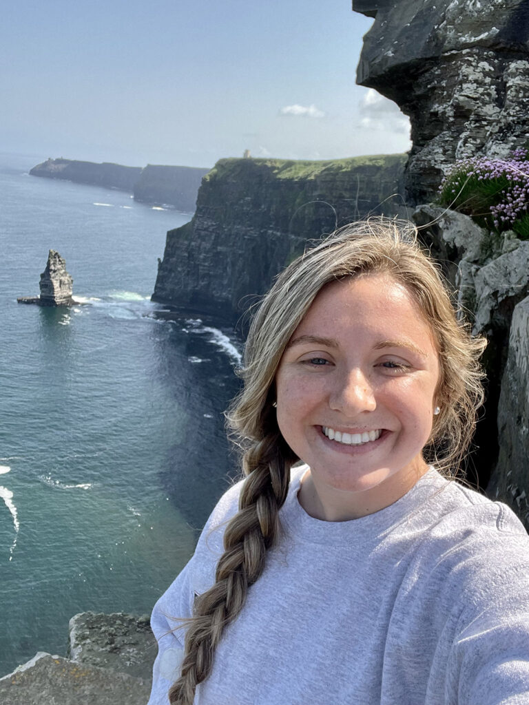 Young woman smiling with Irish coastline in background