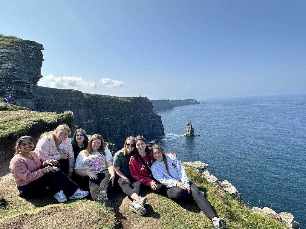 Female study abroad students sitting next to a cliff