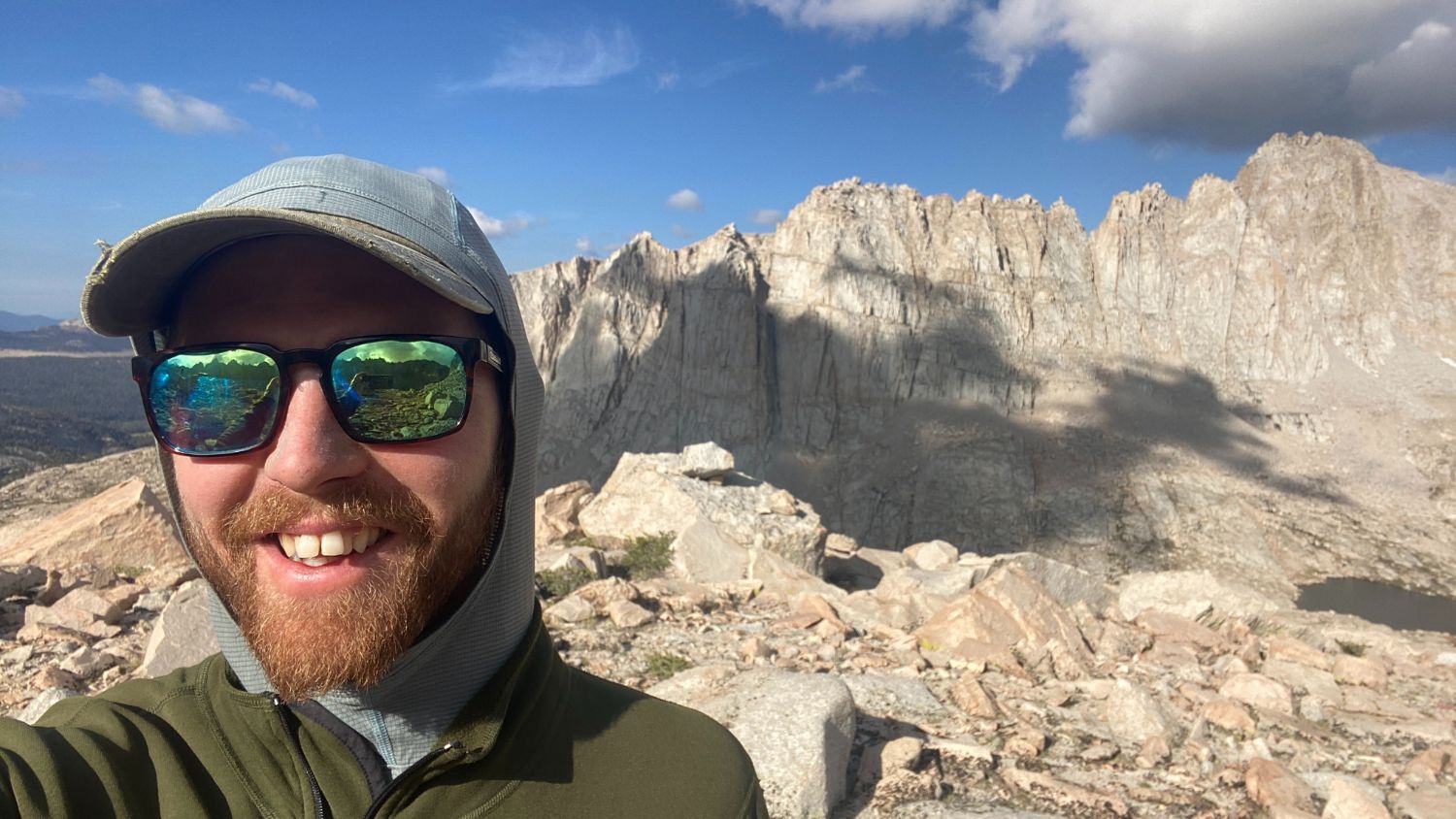 Kaleb Goff taking a selfie at the top of a mountain peak