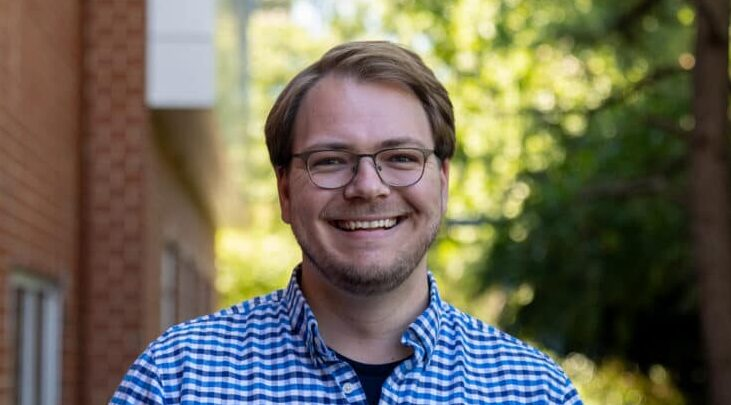 Man with glasses in blue shirt smiling