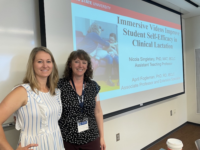 two faculty members from NC State standing in front of a presentation about breastfeeding