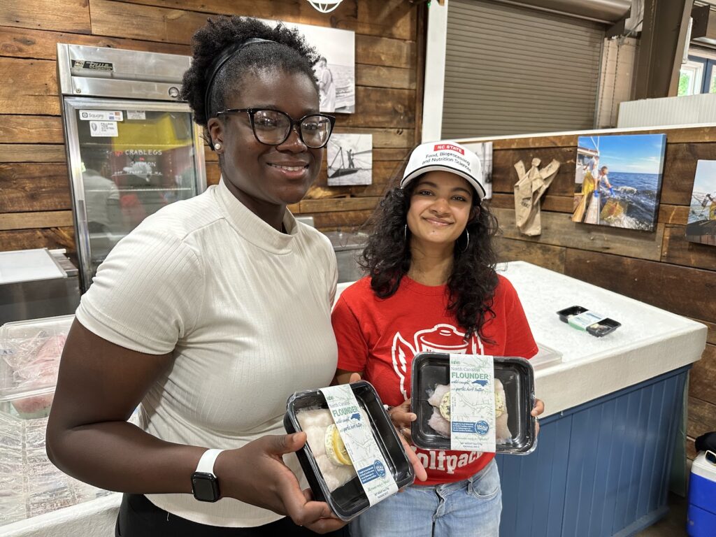 two NC State students holding a frozen seafood meal