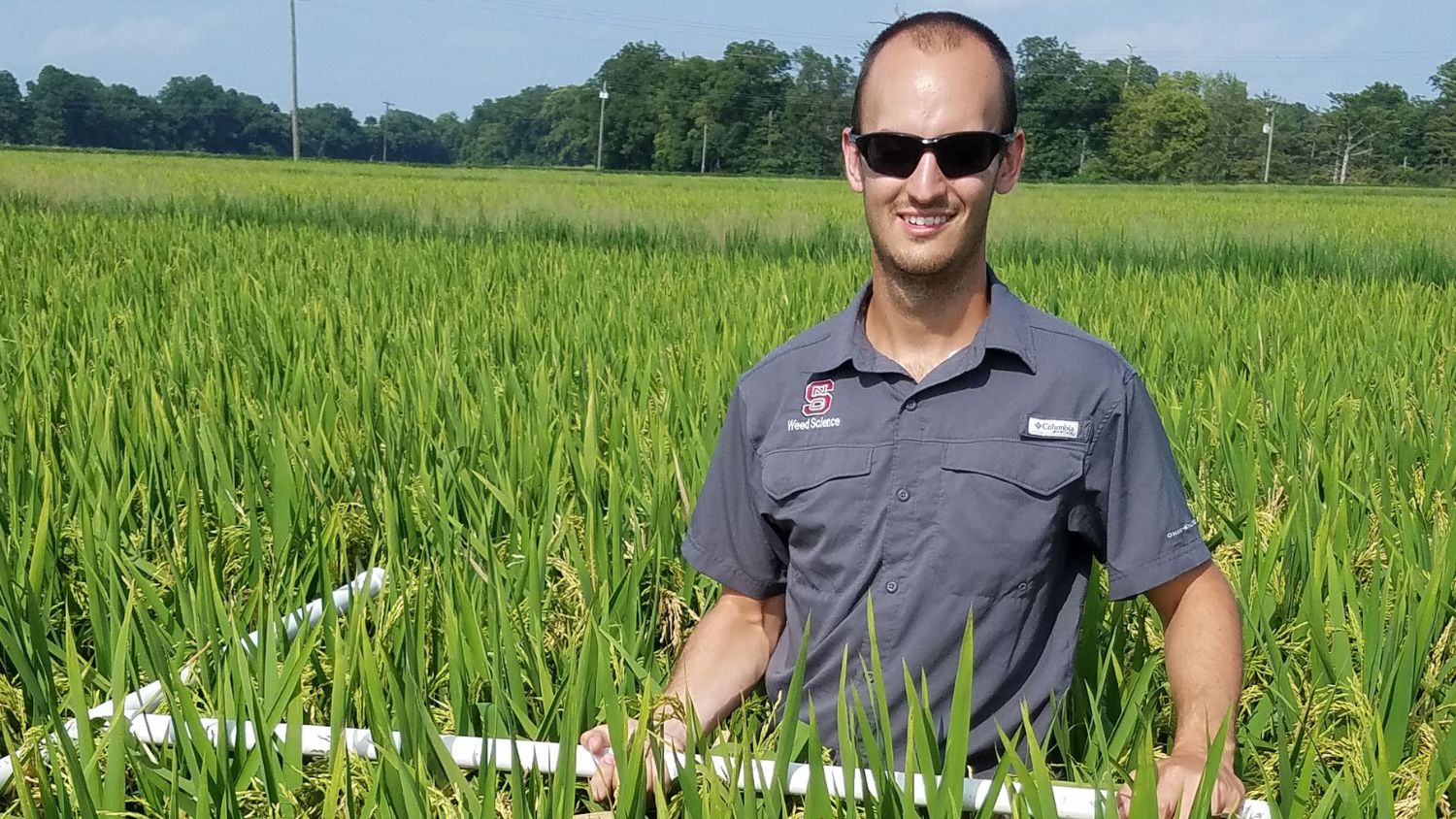 Cole Smith in a field holding an irrigation tube