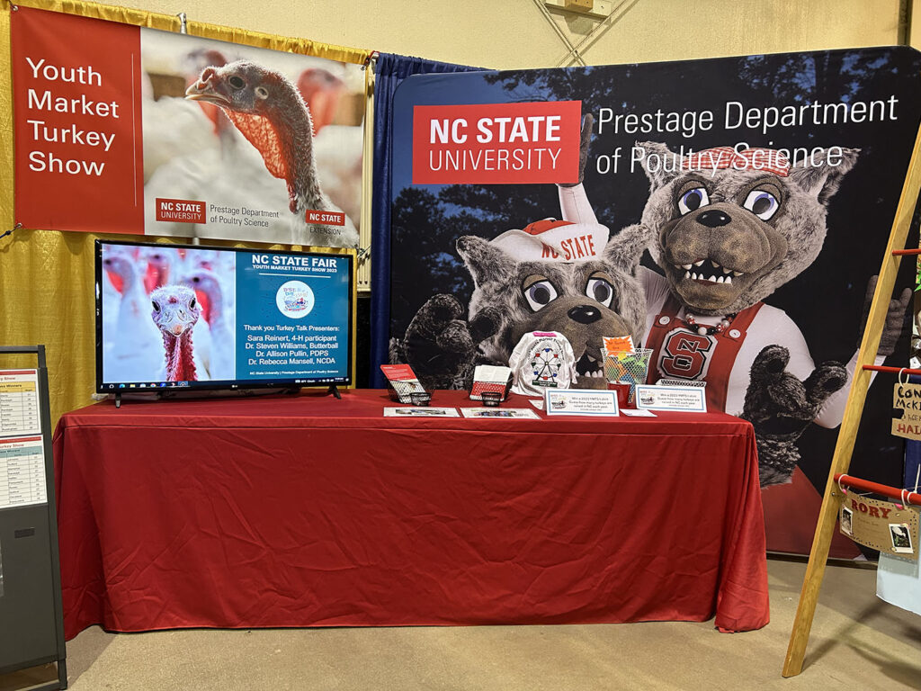prestage department of poultry science booth with images of mr. and mrs. wolf
