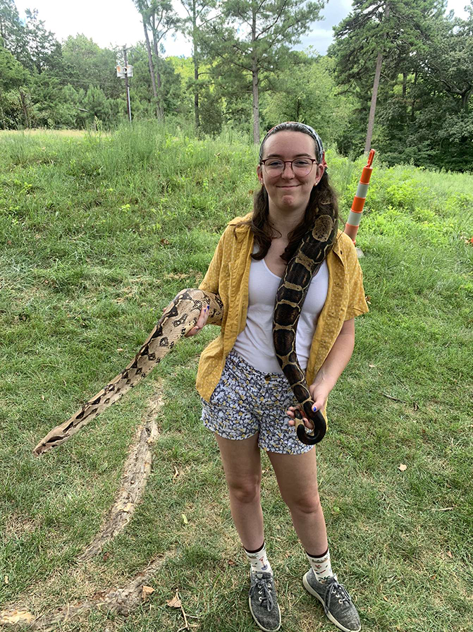 Young woman with glasses holding a boa constrictor