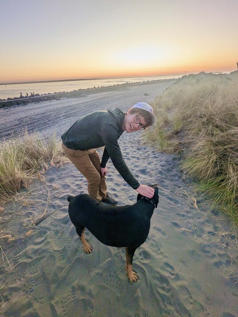 Young man and black dog on the beach