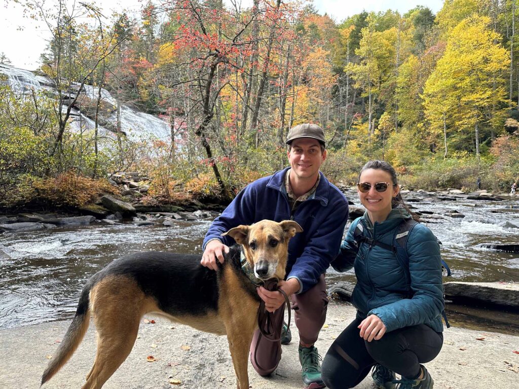 Dog, man and woman in front of a stream in the woods