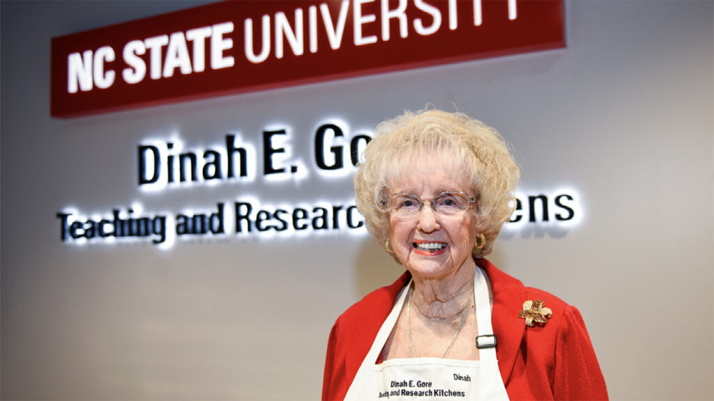 dinah gore stands in front of her name plaque in the kitchen she helped fund