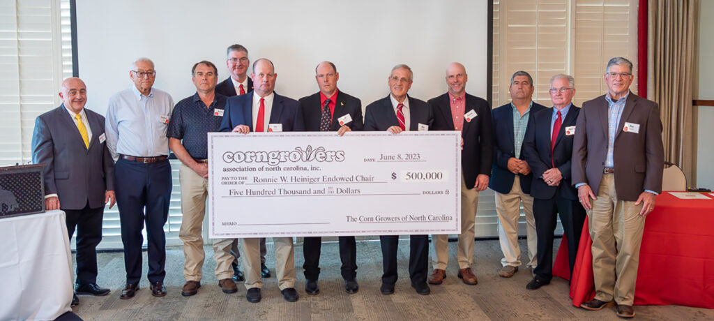 a group of men holding a large ceremonial check from the corn growers association