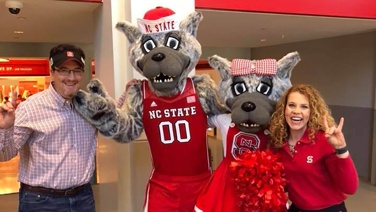 a woman and man stand with NC state mascots Mr. and Mrs. Wuf