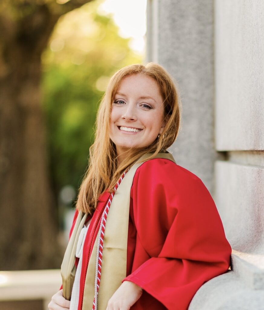 Young woman smiling in red graduation gown