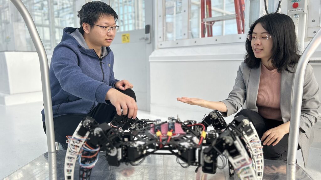 Student and professor examining a spider-like robot.