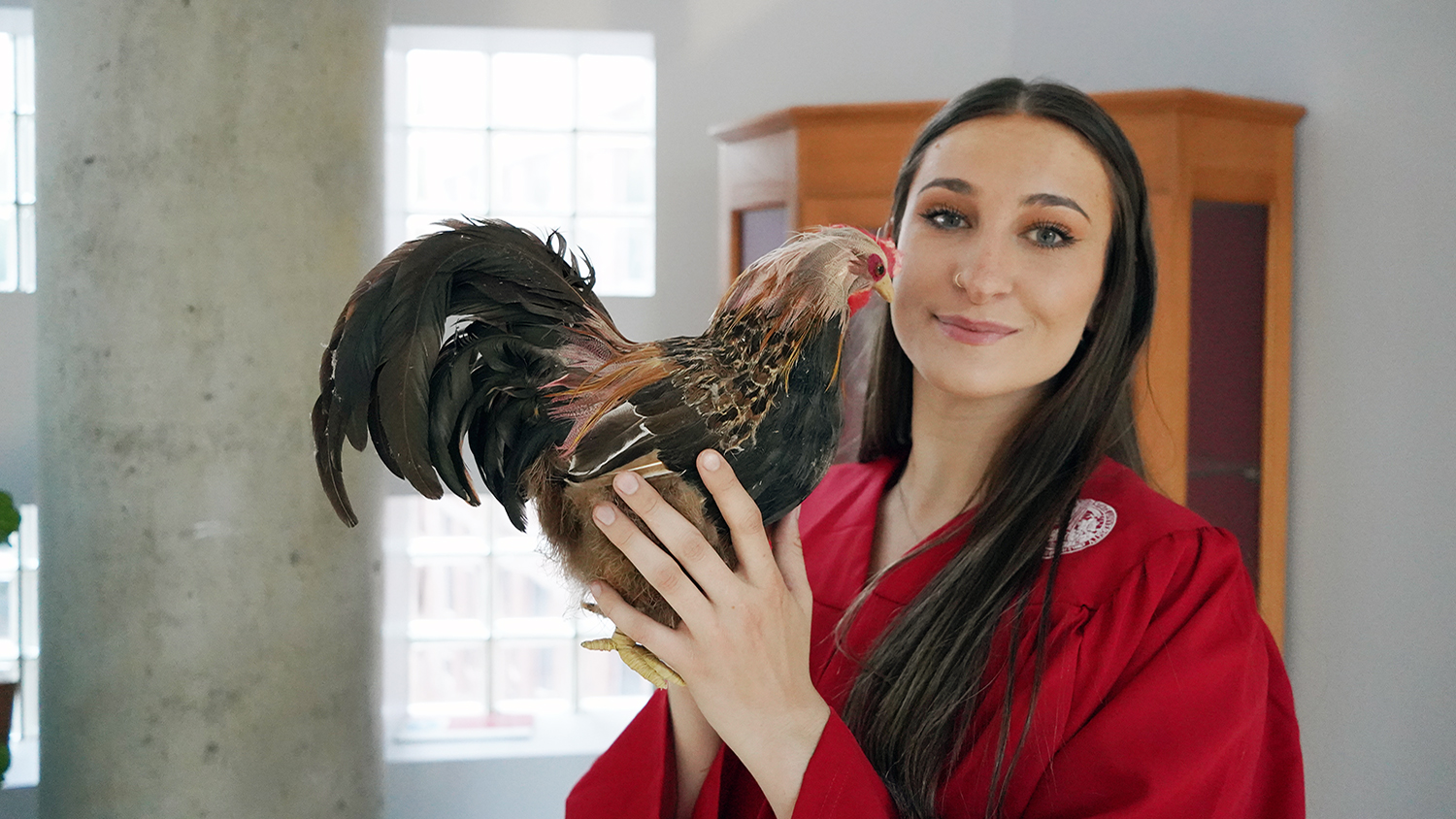 A woman stands with a chicken