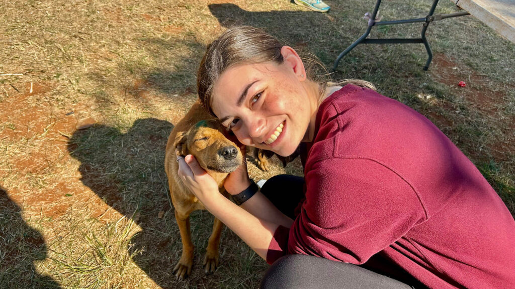 Young woman in burgundy sweatshirt hugging a dog