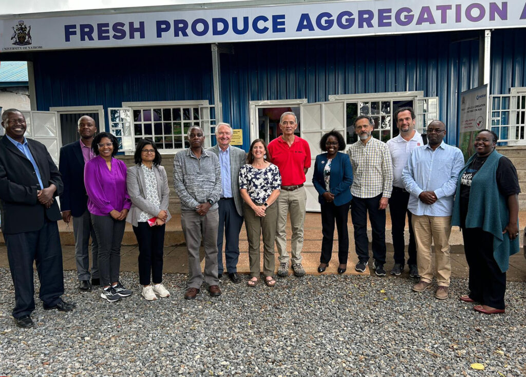 a group of people stand outside of a building that says Fresh produce aggregation