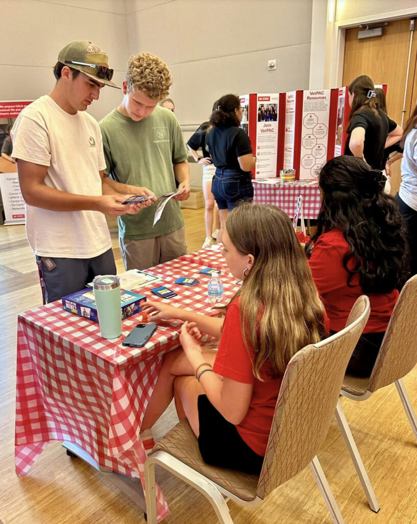 Students stand at an information table with brochures