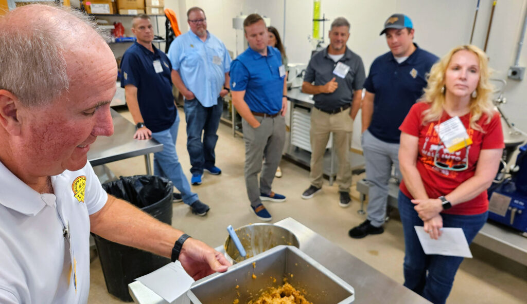 Members of the North Carolina Meat Processors Association line up to view boudin sausage made with salmon