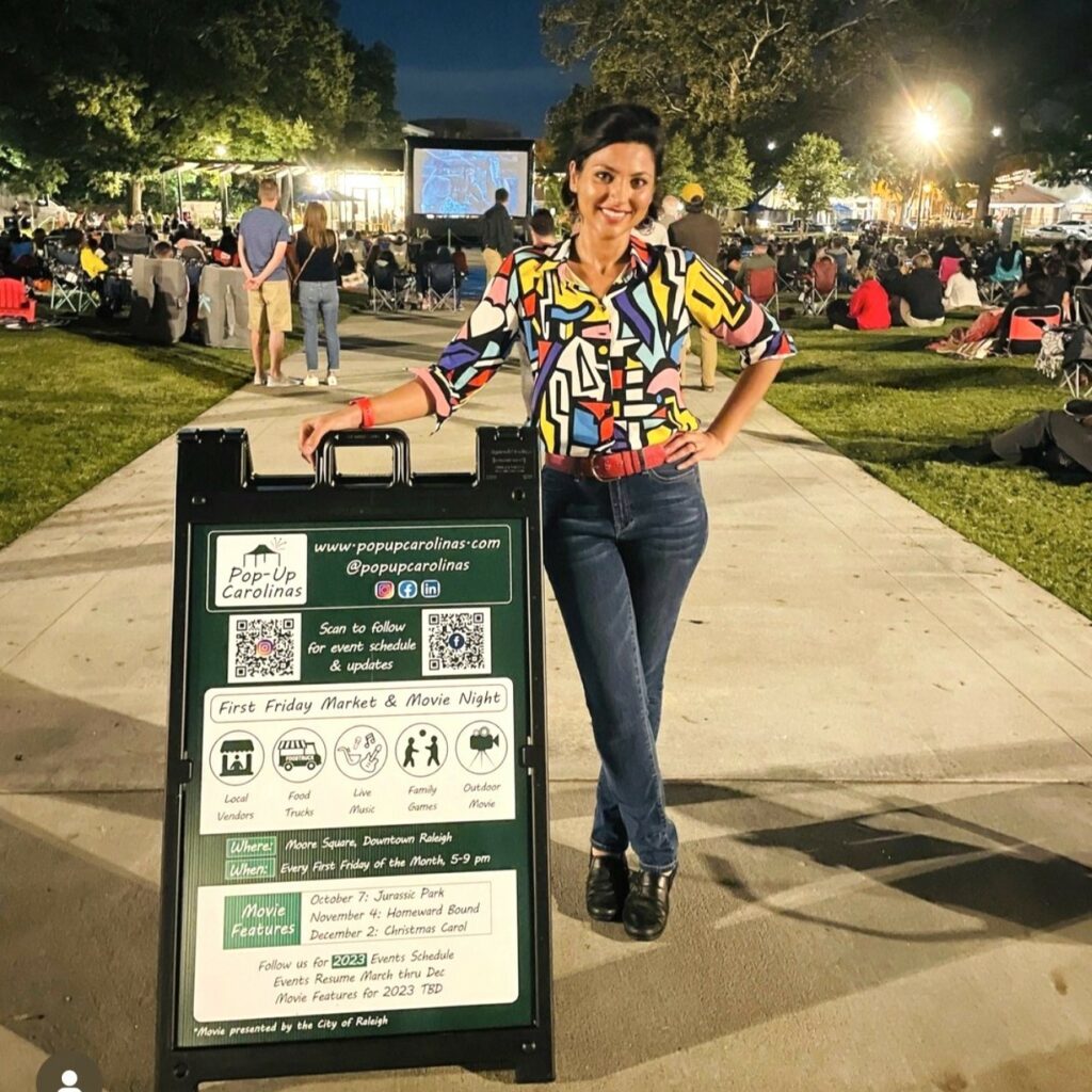 a woman stands outside with a sandwich board sign