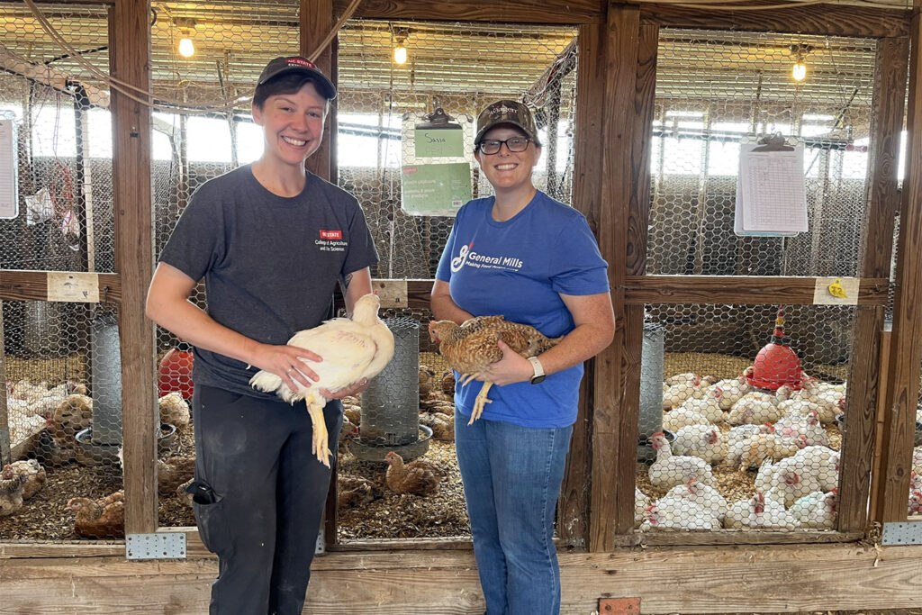 two women hold chickens inside a barn