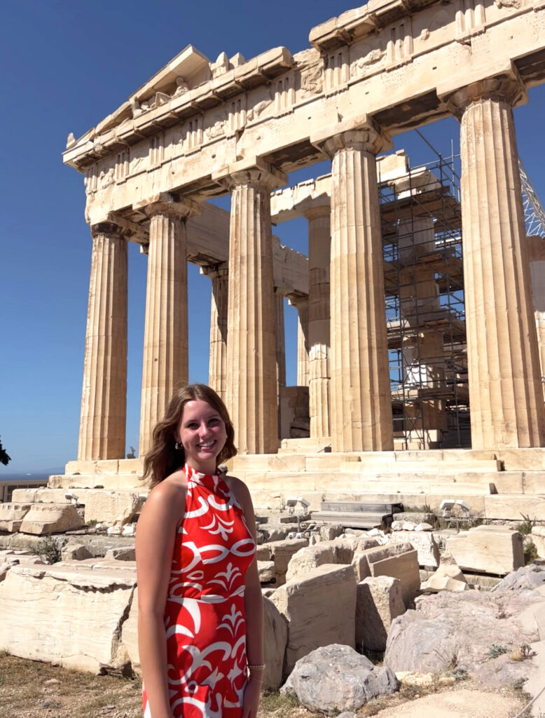 Young woman in red dress in front of ancient ruin