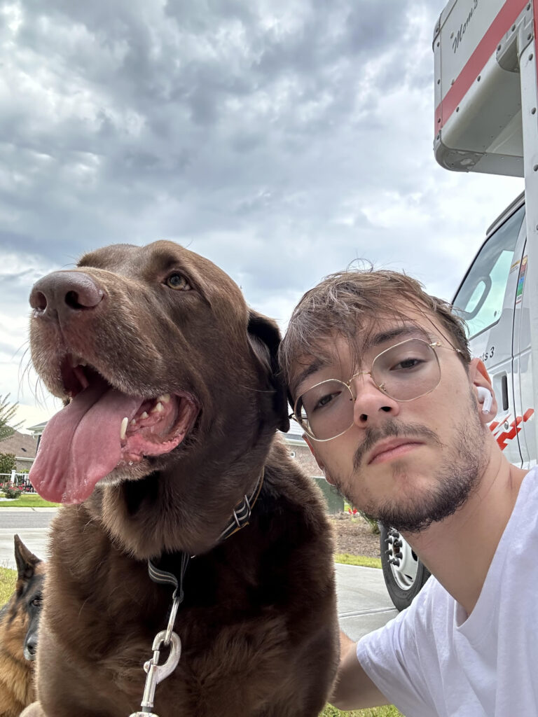 Young man with glasses posing with a brown dog