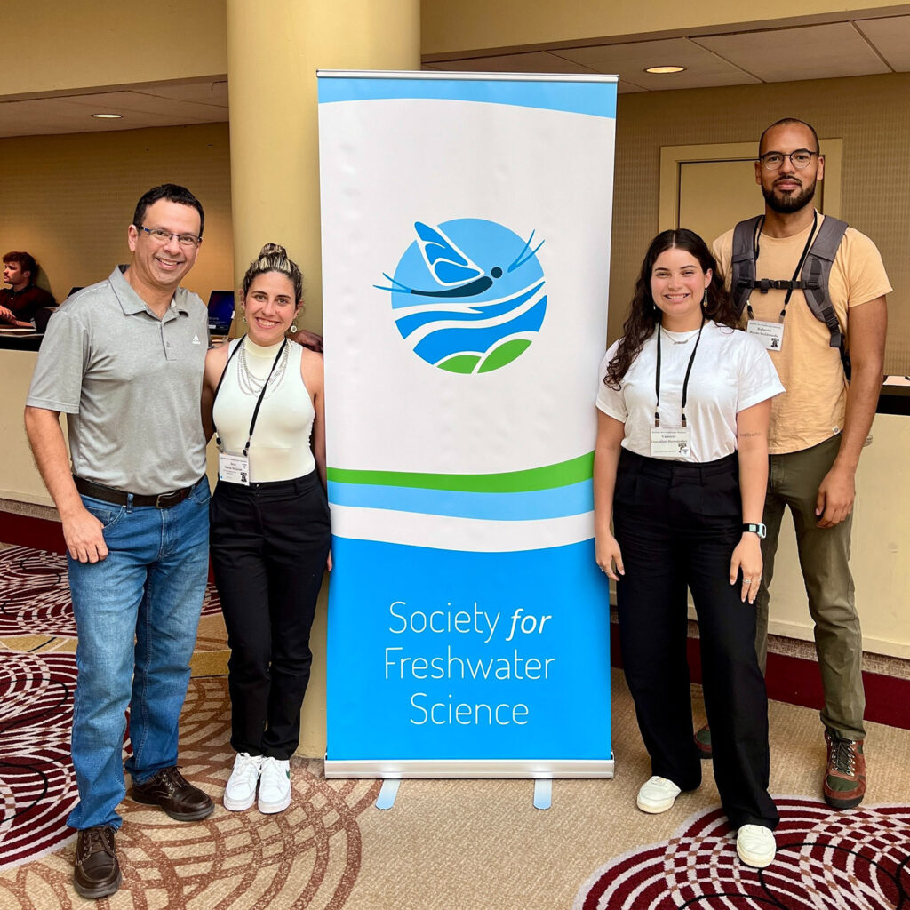 a group of people stand next to a society for freshwater science sign